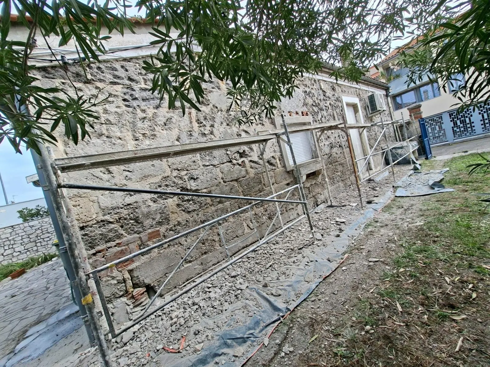 Picage de l'ancien enduit ciment laissant apparaître la pierre sur une maison ancienne à Talence
