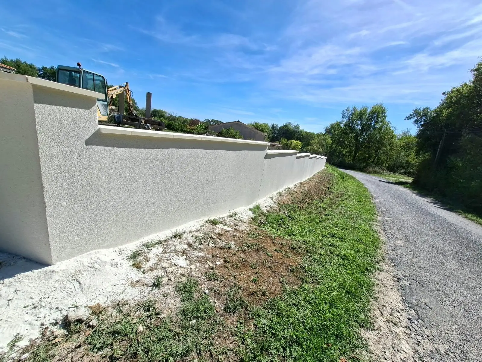 Mur de clôture à redans enduit blanc cassé sur une maison neuve à Lagorce
