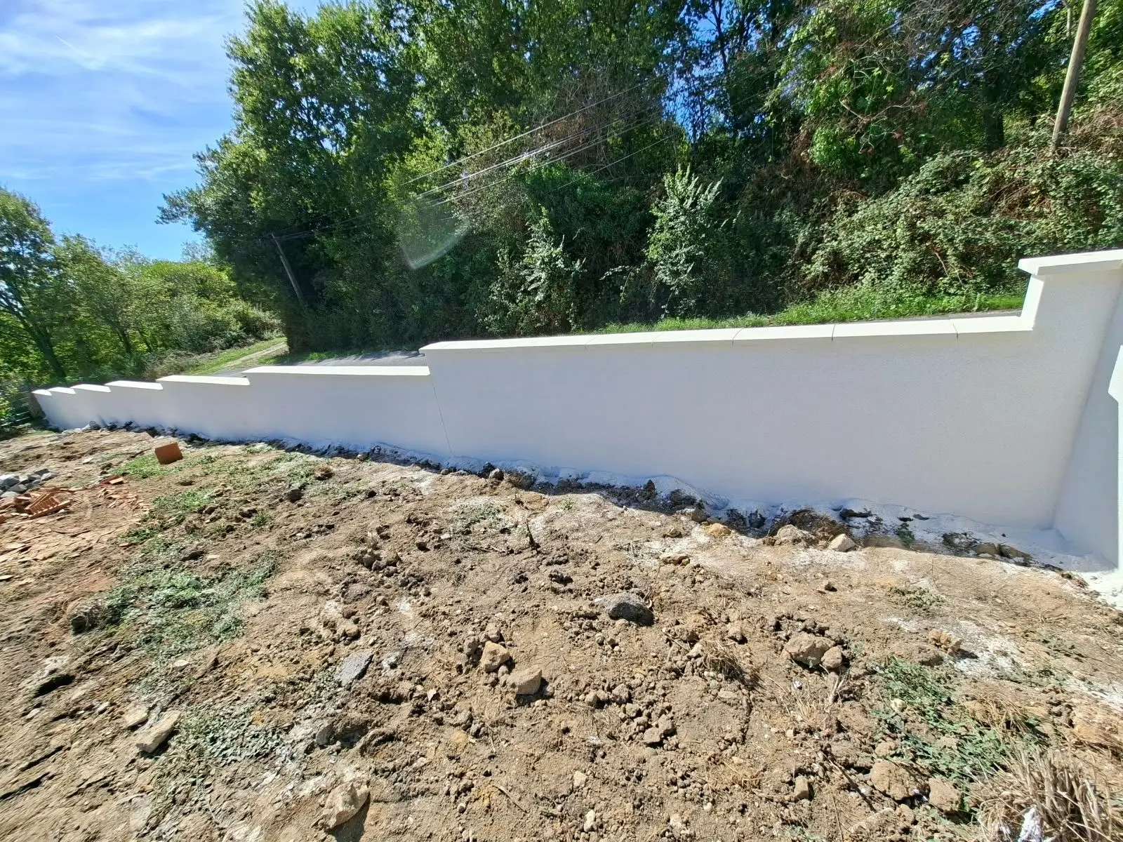 Mur de clôture enduit blanc cassé d'une maison neuve à Lagorce