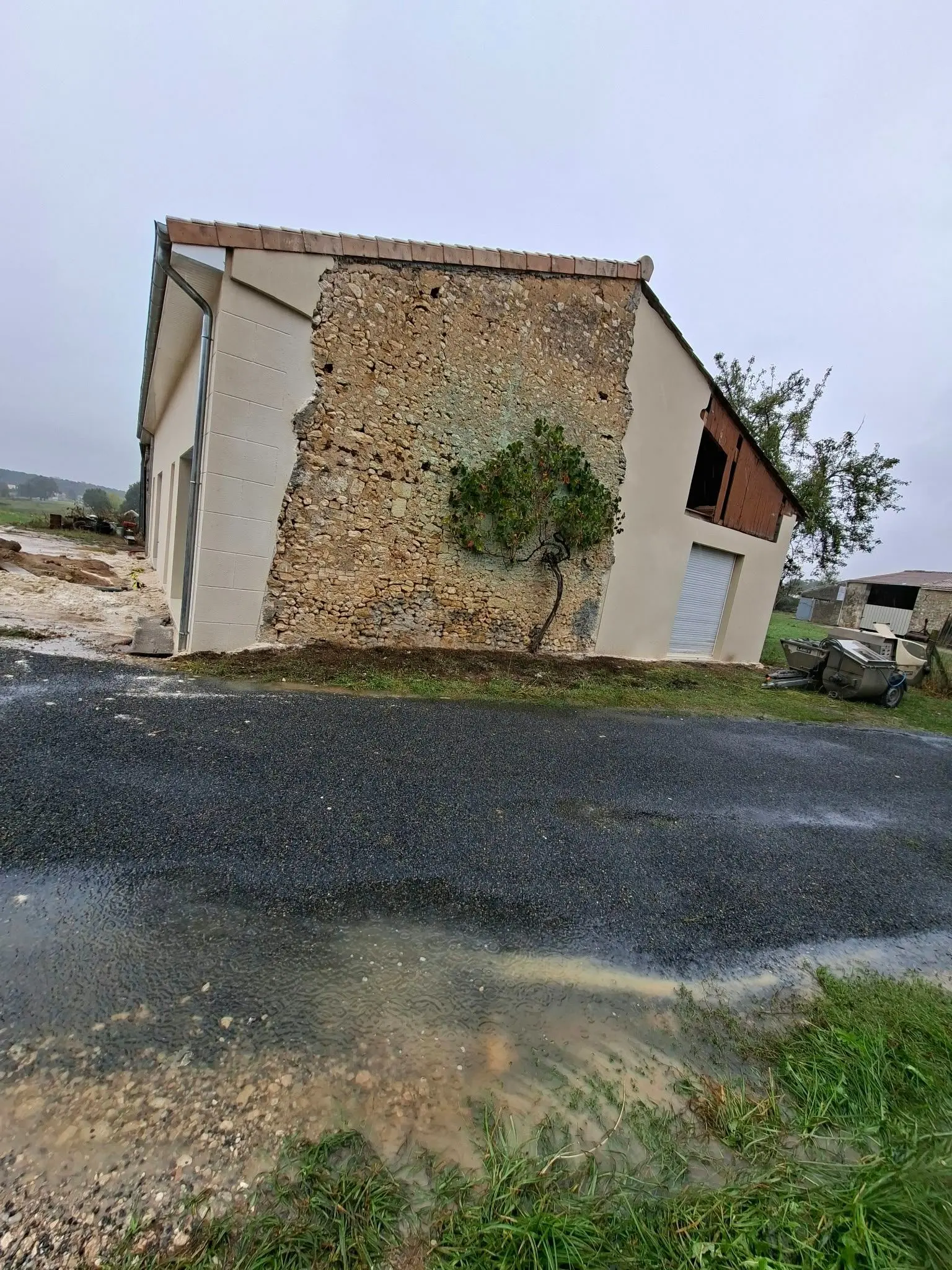 Pignon enduit monocouche gratté fin ton pierre de la partie neuve d'une maison à Montendre