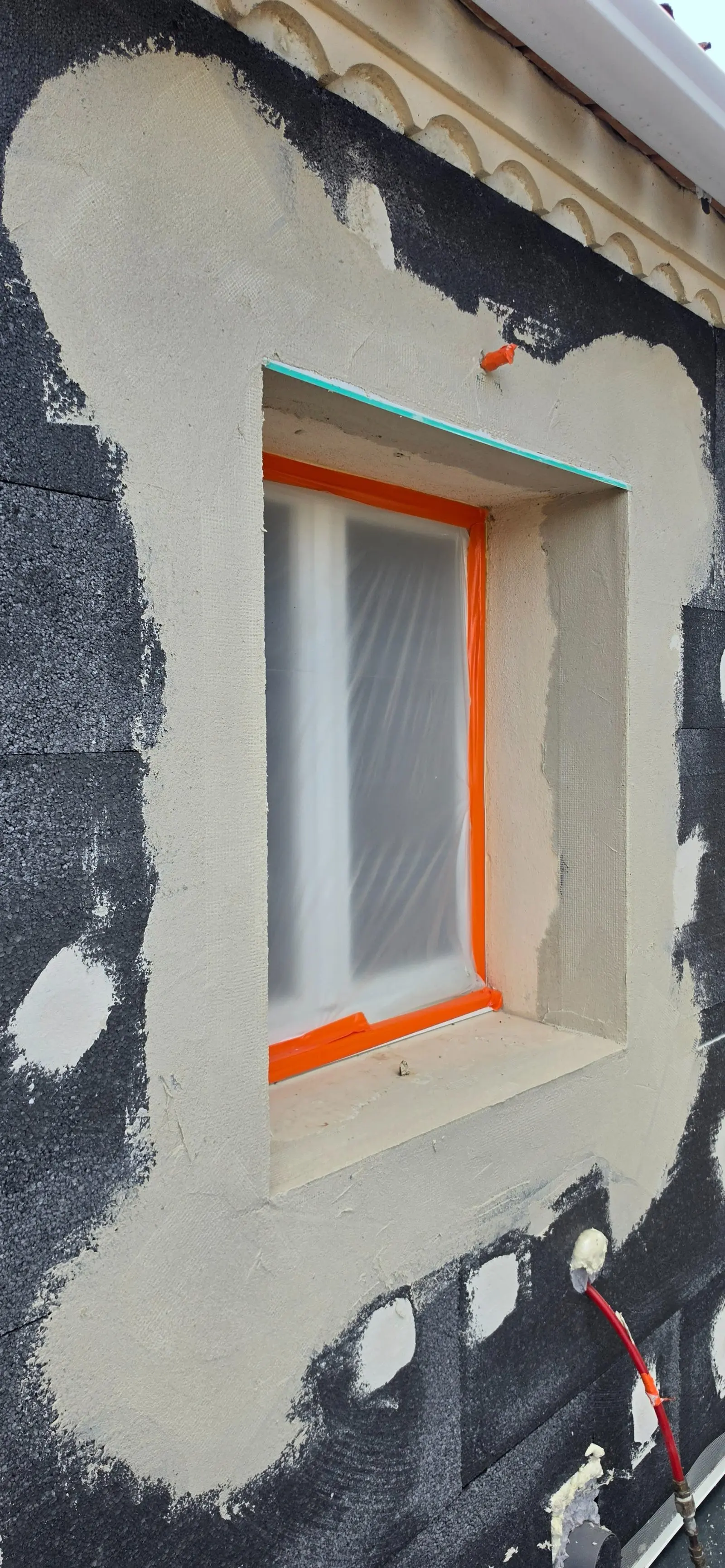 Détail de l'encadrement d'une fenêtre protégée pendant les travaux d'isolation thermique par l'extérieur à Coutras