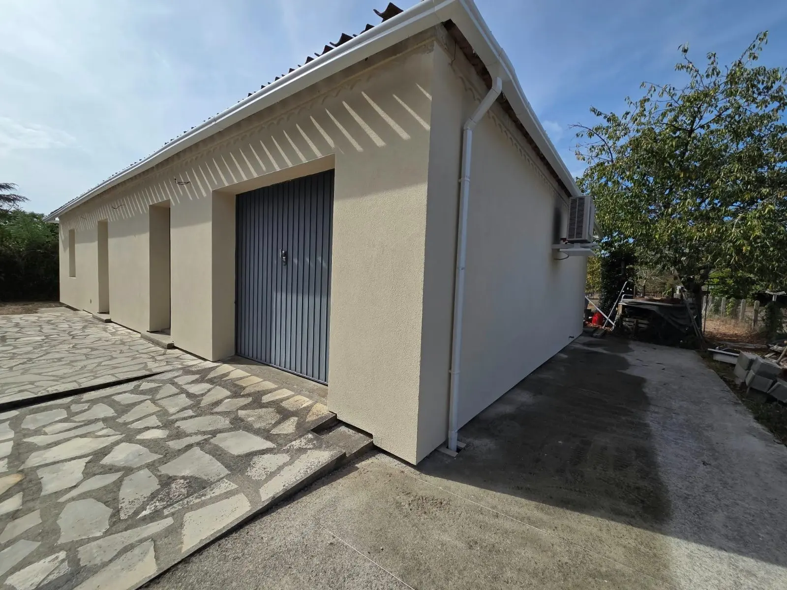 Façade latérale avec porte de garage d'une maison ancienne isolée par l'extérieur à Coutras